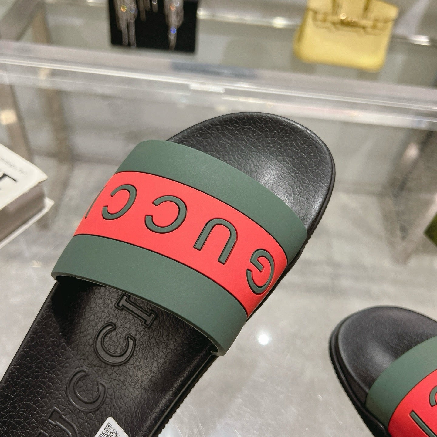 Close-up of Gucci sandal strap with red “GUCCI” letters on green base