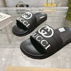 Black Gucci slide sandals, front view of two sandals with white logo bands