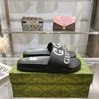 Black Gucci slide sandals on box, textured footbed with white logo strap