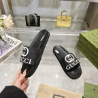 Black Gucci slide sandals with thick strap and white Gucci logo lettering