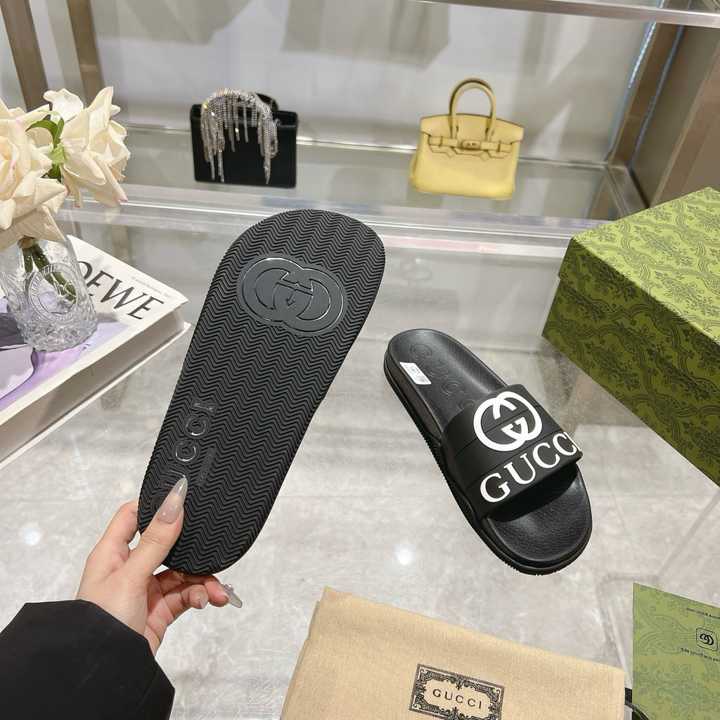 Black Gucci slide sandal soles, textured tread with Gucci emblem on footbed