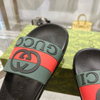 Black Gucci slide sandal with green strap, red stripe, and GG logo detail.