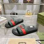 Black Gucci slide sandals, green top strap with red stripe and molded rubber sole.
