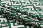 Green fabric with white geometric motif, textured weave close-up