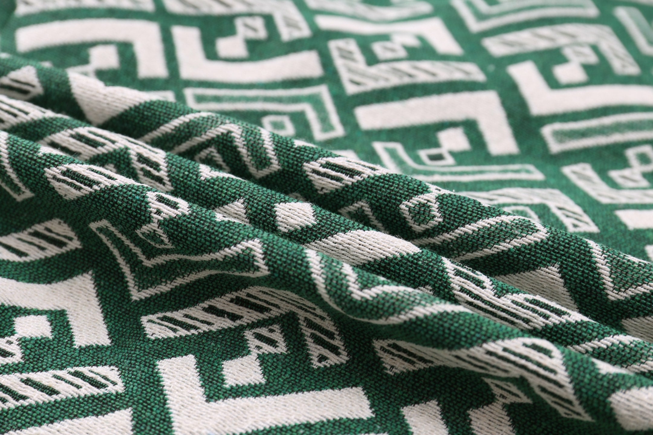 Green fabric with white geometric motif, textured weave close-up