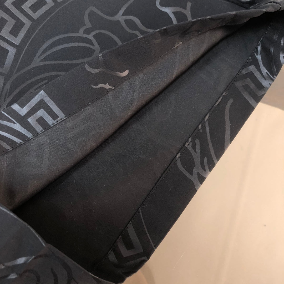 Versace black shorts close-up showing side seam and continuous all-over pattern print.