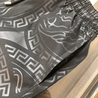 Versace shorts with bold all-over Greek key and baroque-style pattern in dark gray.