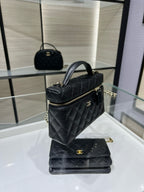 Black quilted Chanel top-handle handbag with zipper, gold-tone hardware, and chain strap