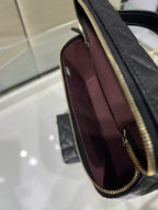 Side view of black Chanel handbag with gold zipper and maroon interior lining