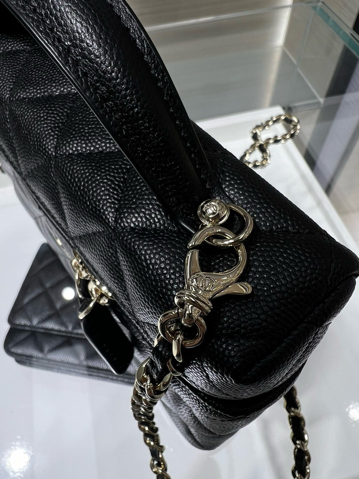 Close-up of black quilted Chanel handbag with gold turn-lock and chain strap