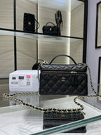 Black quilted Chanel handbag with top handle, chain strap, and gold-tone flap hardware