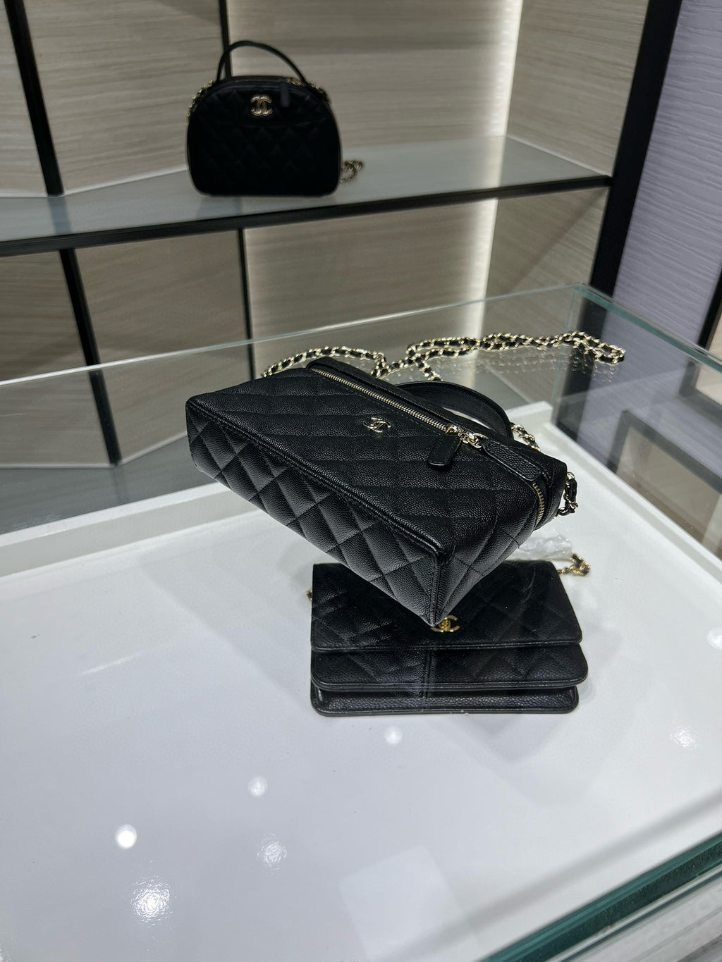 Black quilted Chanel handbag with top handle, chain strap, and gold-tone front detail