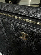 Close-up of black quilted Chanel handbag with gold-tone zipper and flap detail