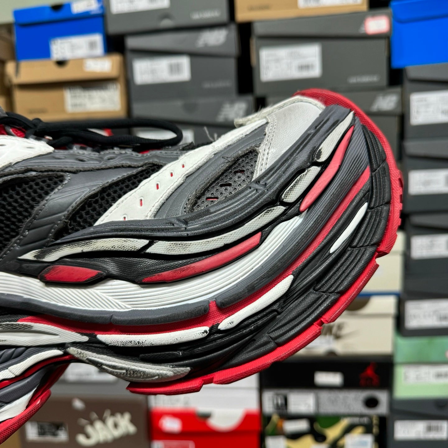 Side view of chunky sneaker with layered ridged sole in black, gray, and red