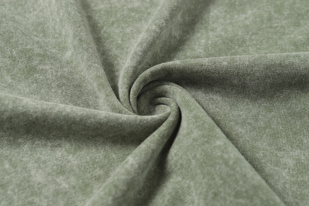Sage green T-shirt fabric close-up with soft knit texture twist