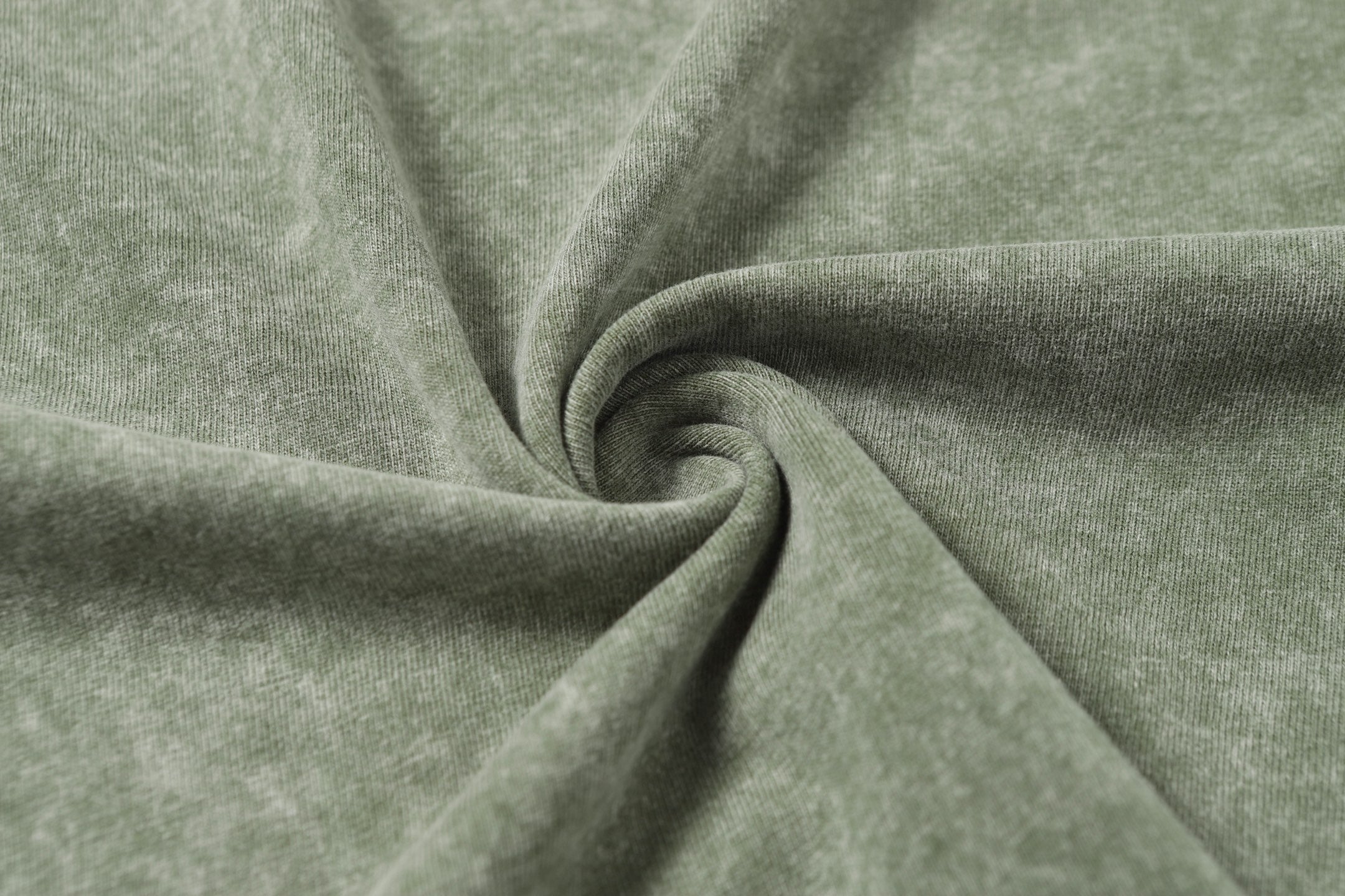 Sage green T-shirt fabric close-up with soft knit texture twist