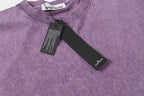Stone Island T-shirt neckline with attached hang tags on lavender fabric.