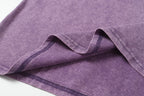 Lavender T-shirt fabric folds with visible stitching along the hem.