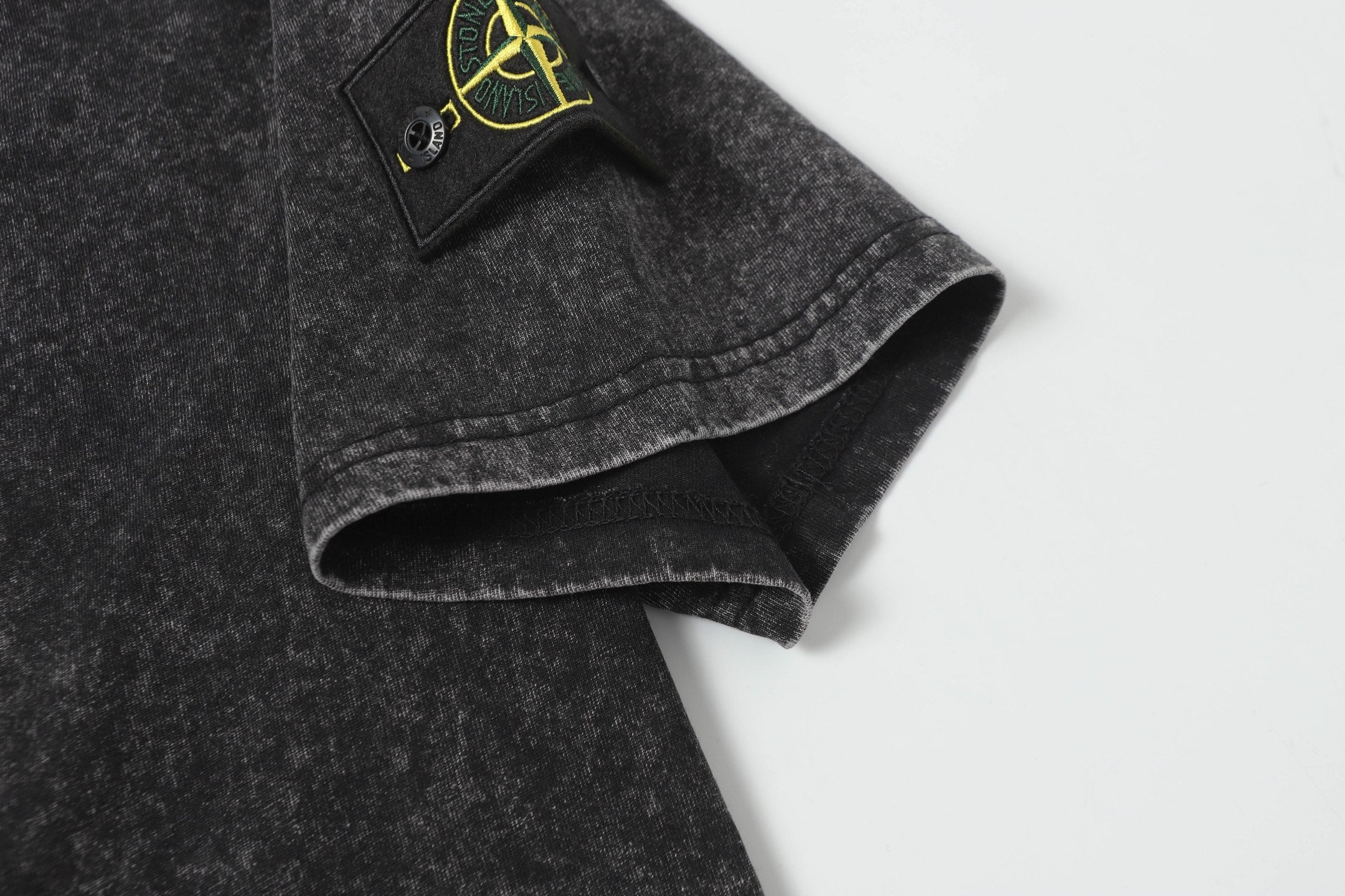 Dark charcoal T-shirt hem and sleeve cuff detail, speckled fabric texture