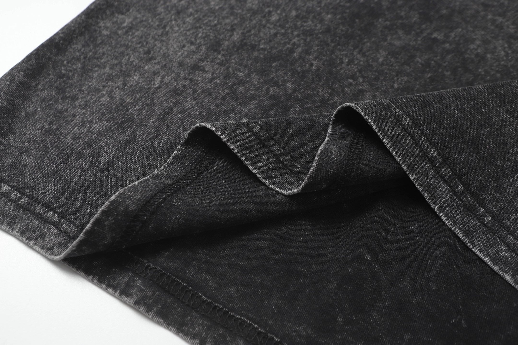 Dark charcoal T-shirt fabric fold and seam detail, speckled texture