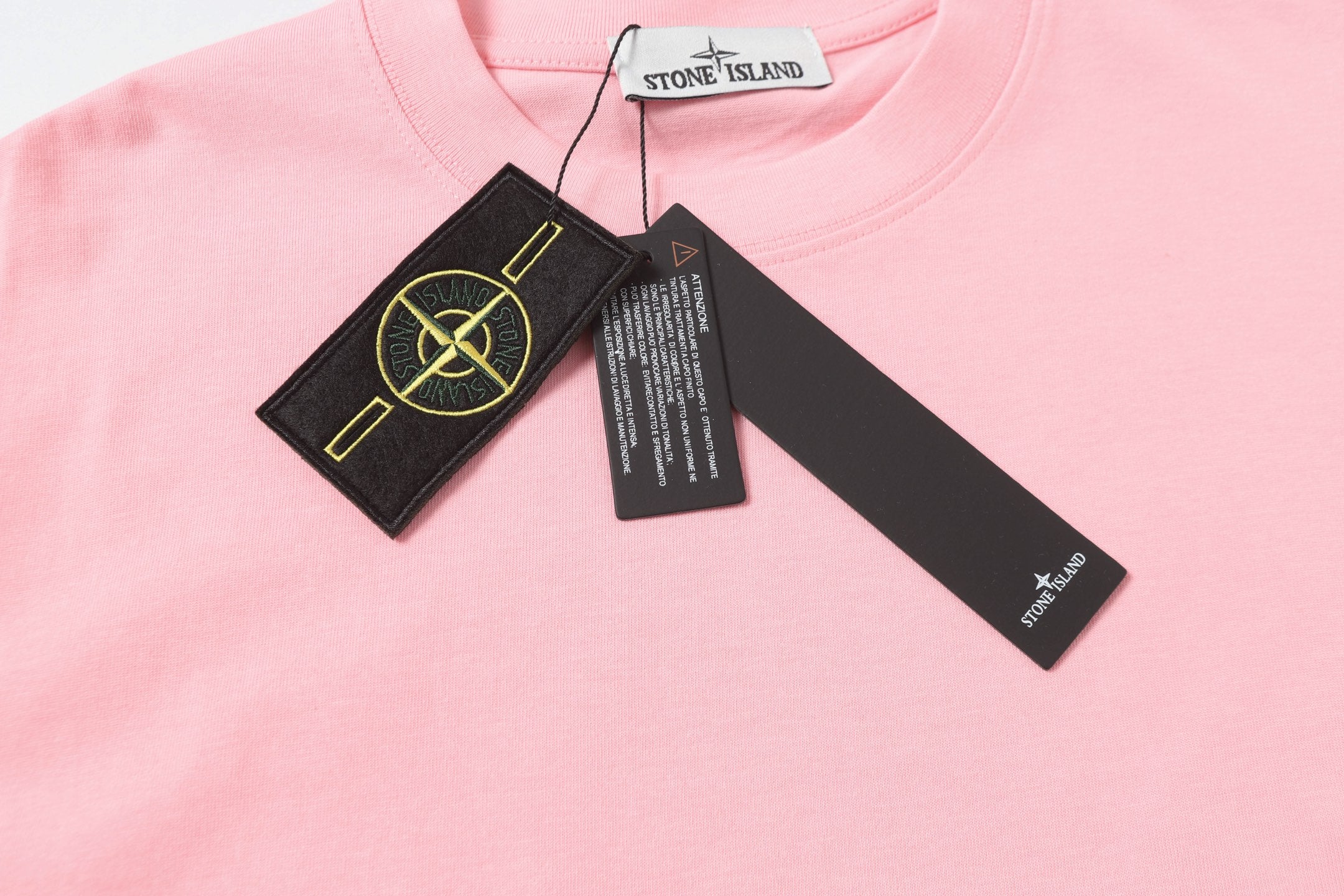 Pink T-shirt front with Stone Island neck label and black hang tags