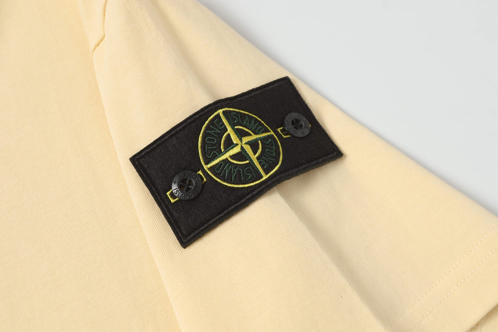 Cream T-shirt with black logo patch detail near the sleeve