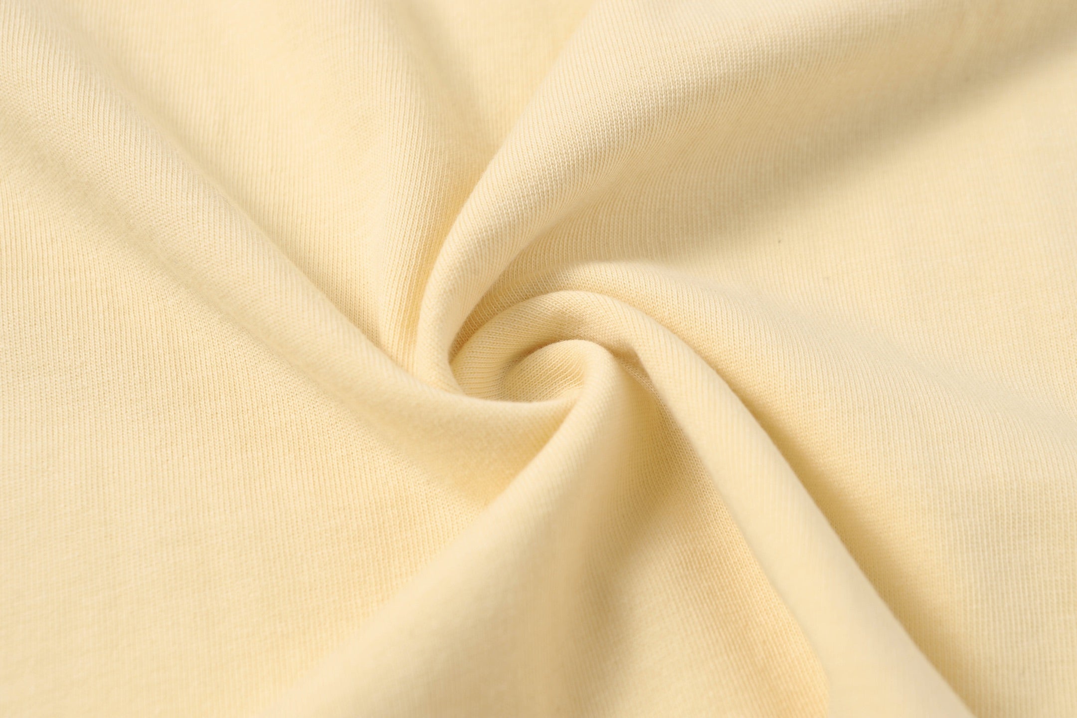 Cream cotton T-shirt fabric close-up with soft knit texture