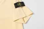 Cream T-shirt folded with black logo patch on the front