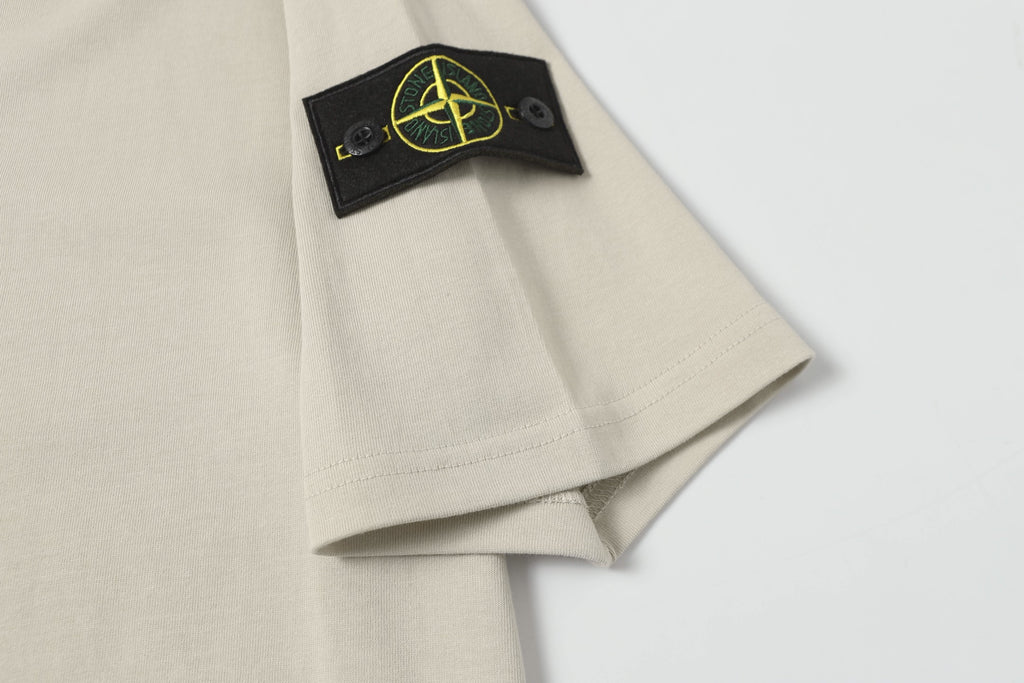 Light beige T-shirt sleeve with black patch and yellow logo