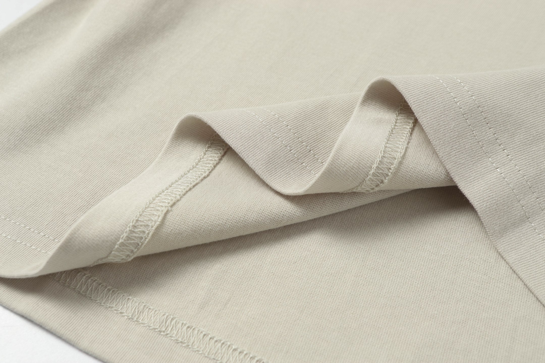 Light beige T-shirt hem stitching and fabric weave, close-up