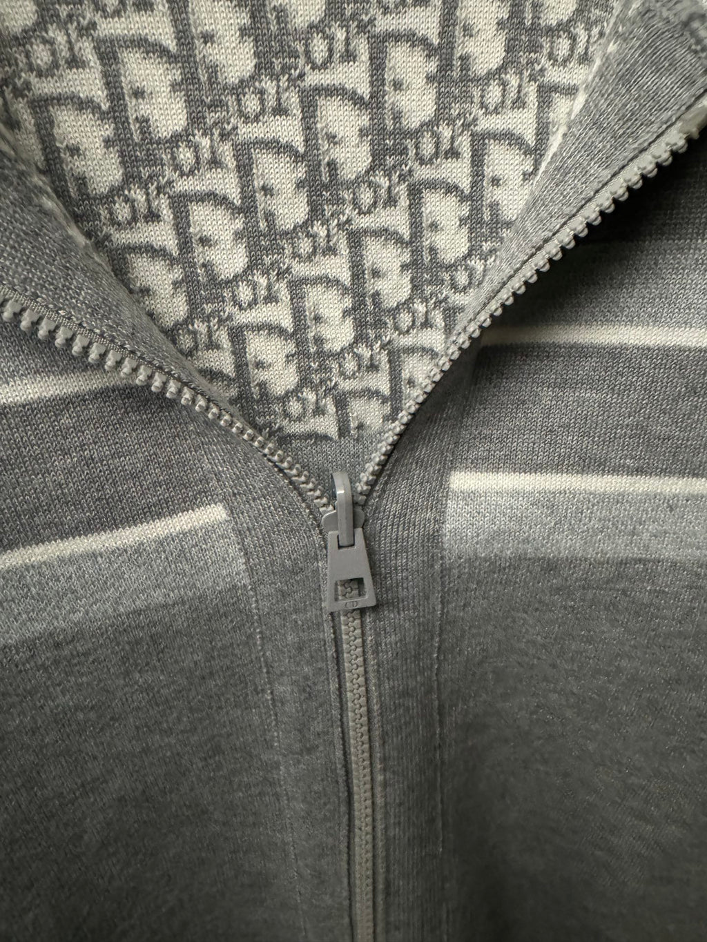 Close-up of hoodie zipper and off-white stripe on gray fabric