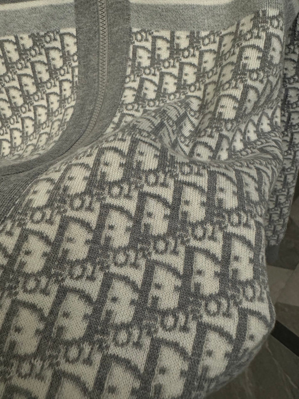 Close-up of Dior monogram pattern panel on gray hoodie