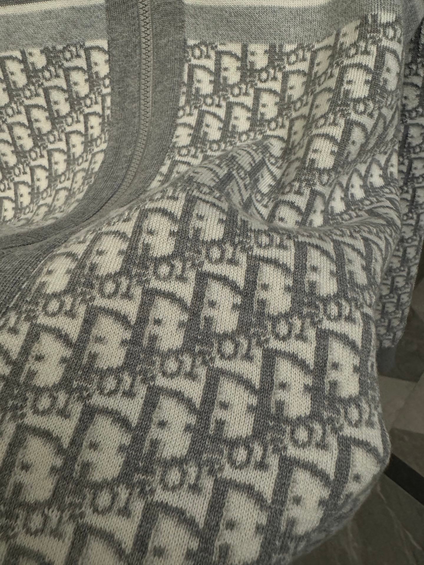 Close-up of Dior monogram pattern panel on gray hoodie