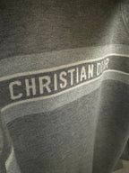 Close-up of CHRISTIAN DIOR logo stripe on gray hoodie