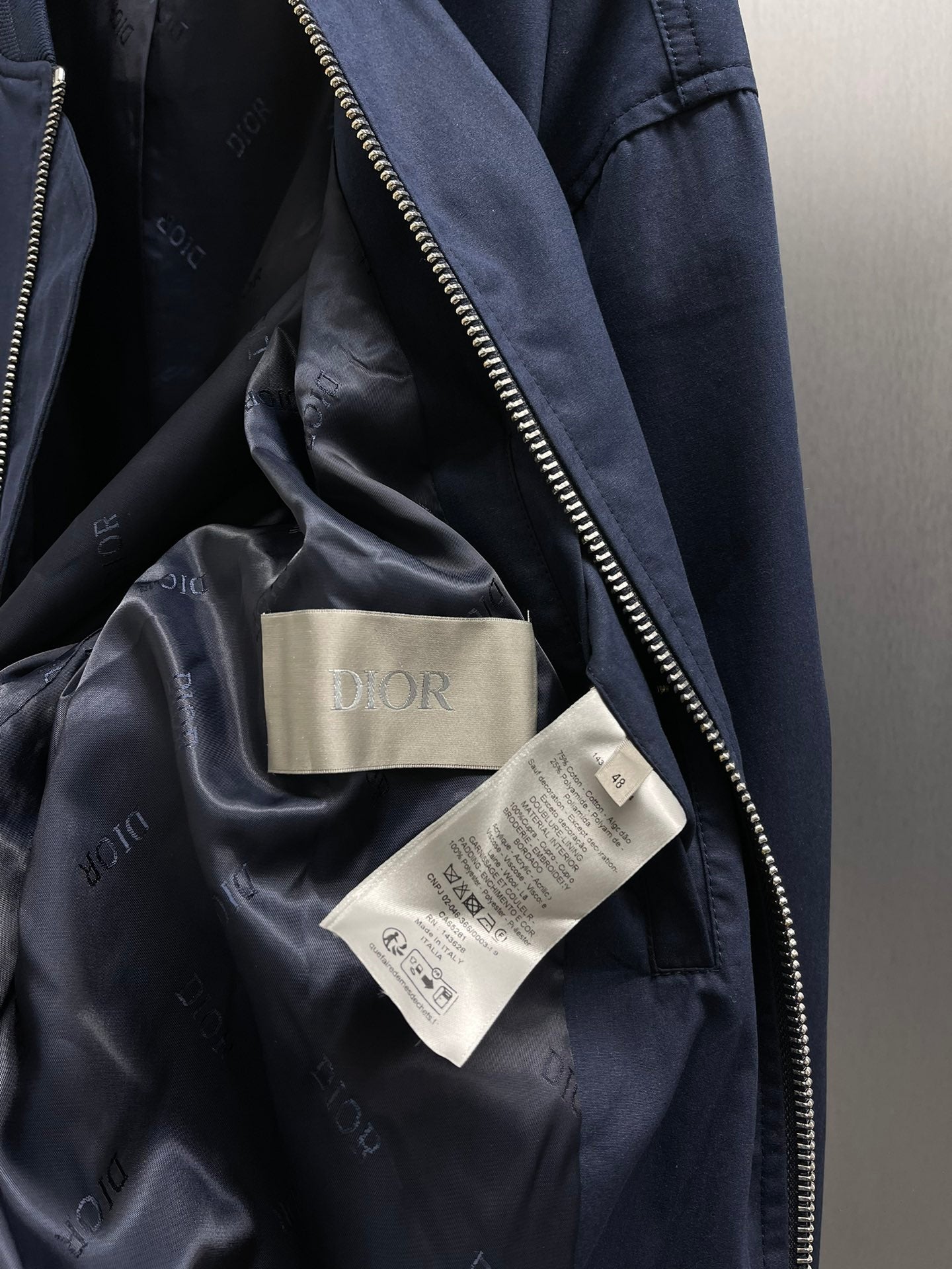 Navy bomber jacket interior lining with Dior tag labels and inner pocket seam.