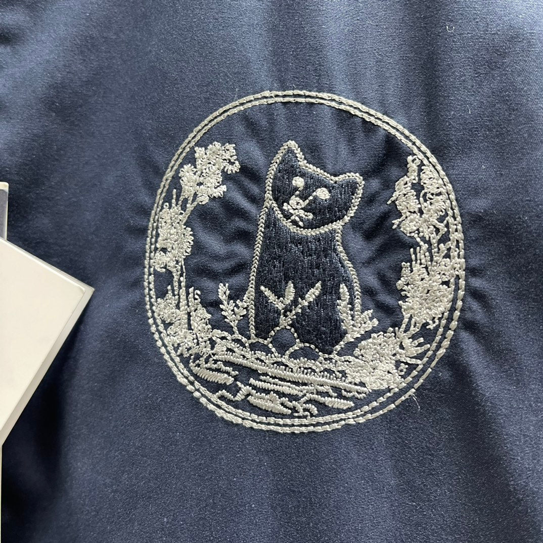 Embroidered Dior crest patch on navy bomber jacket front, bordered floral details.