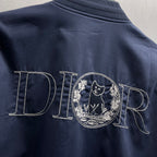 Navy bomber jacket back with stitched 'DIOR' text and embroidered crest emblem.