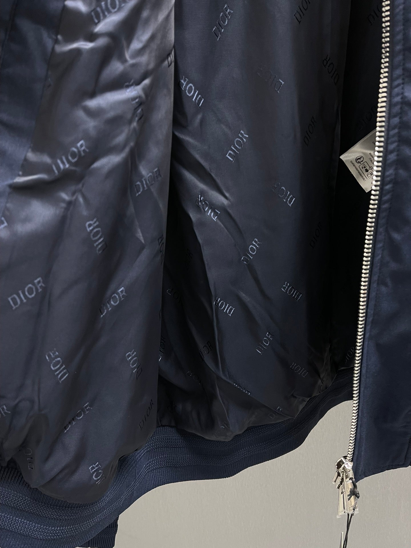 Navy bomber jacket lining with repeating Dior logo pattern and inner pocket opening.