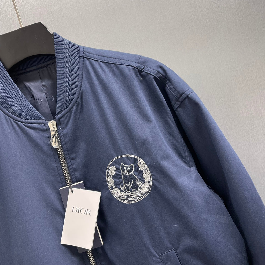 Navy bomber jacket with ribbed trim collar and embroidered Dior crest on chest.