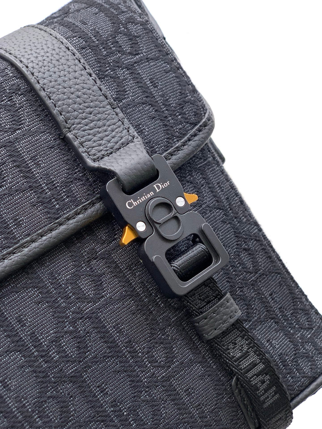 Dior strap hardware with engraved logo plate on dark gray monogram bag