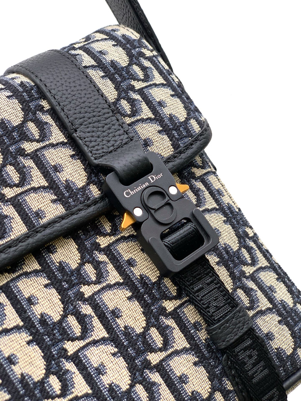 Dior bag close-up: monogram canvas with black leather strap and gold-tone detail
