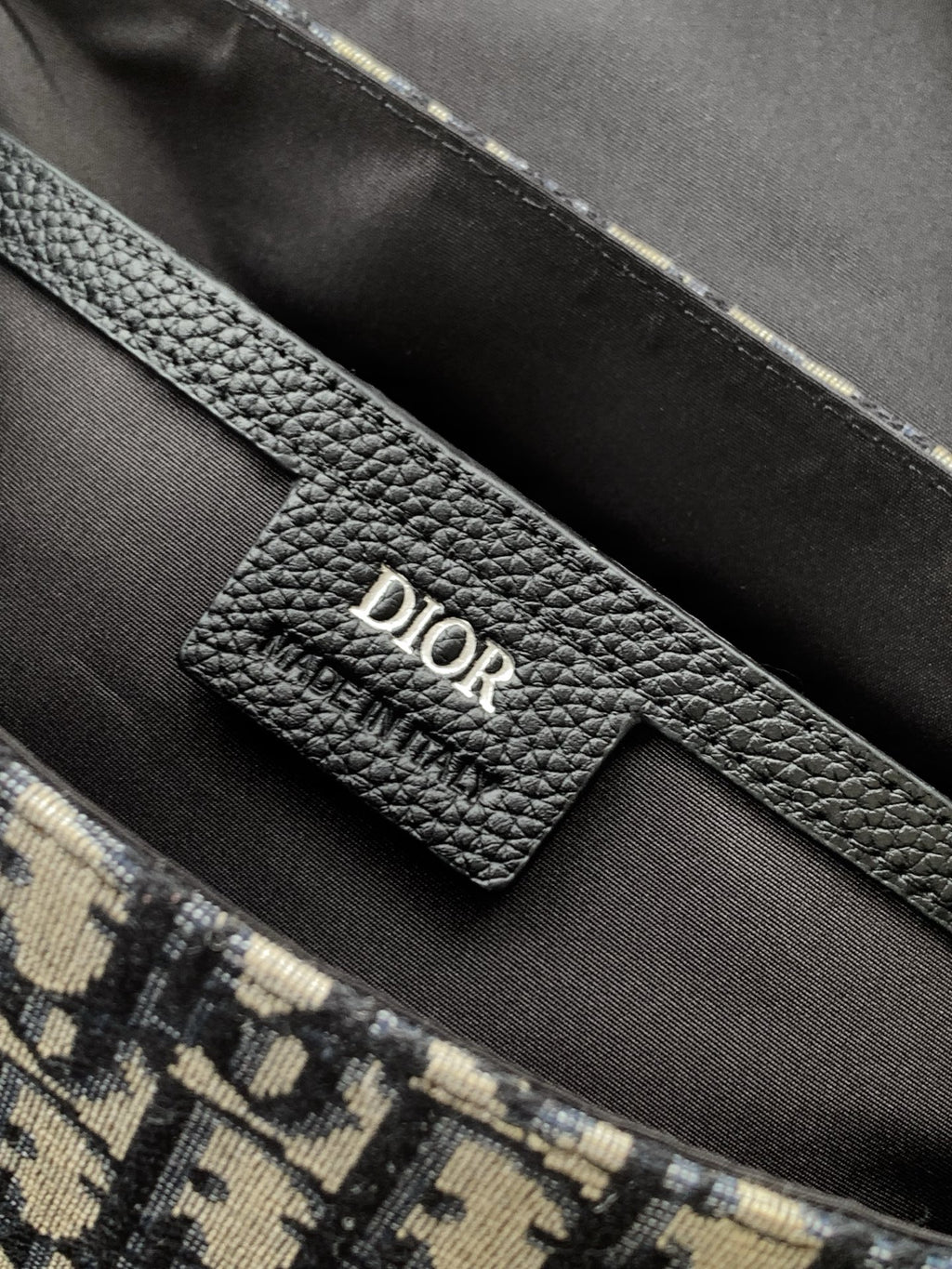 Inside view of Dior bag with black leather label and monogram canvas pocket edge