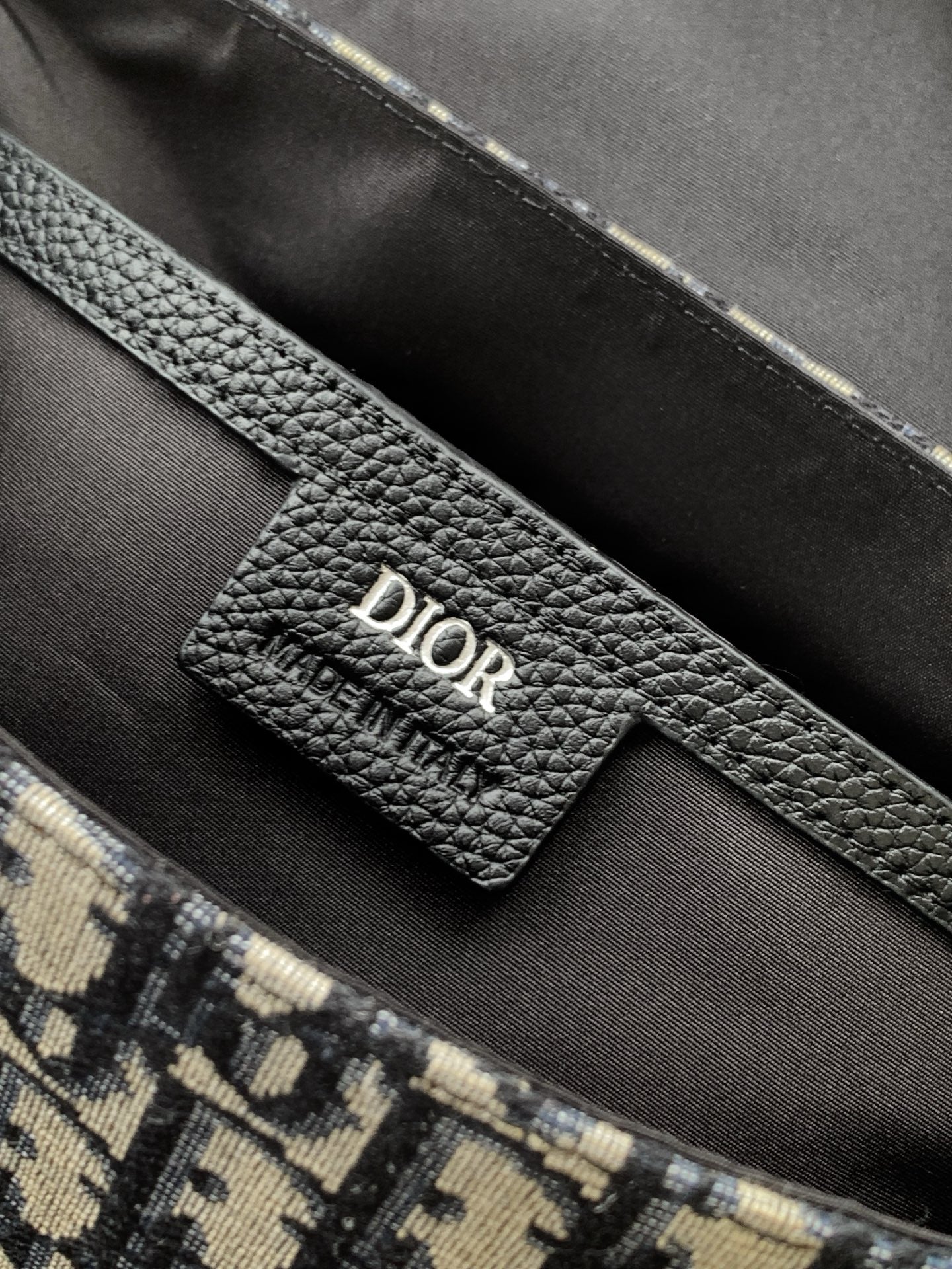Inside view of Dior bag with black leather label and monogram canvas pocket edge