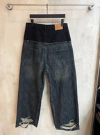 Distressed two-tone denim jeans with dark waistband and lighter faded panels on legs.