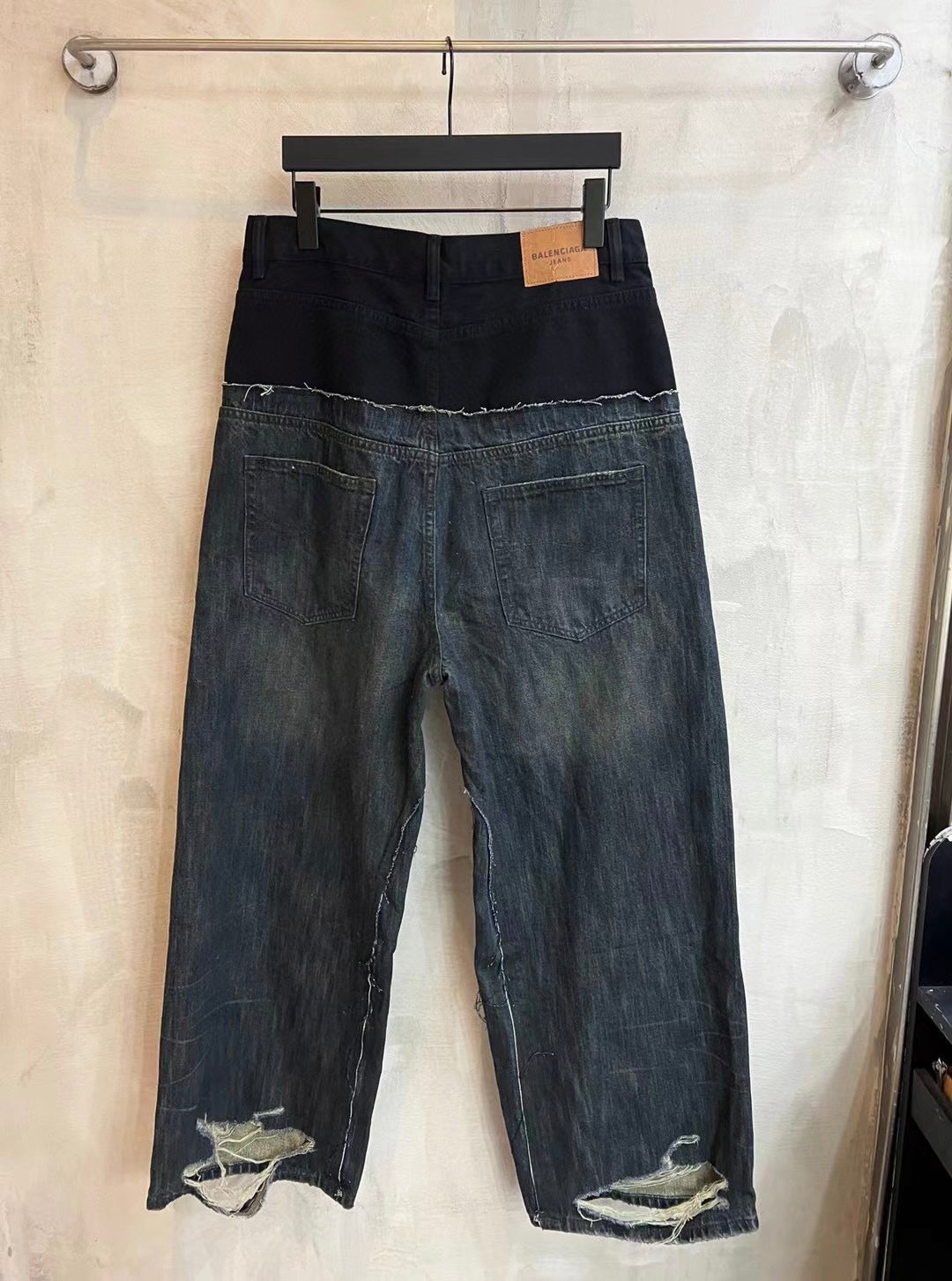 Distressed two-tone denim jeans with dark waistband and lighter faded panels on legs.