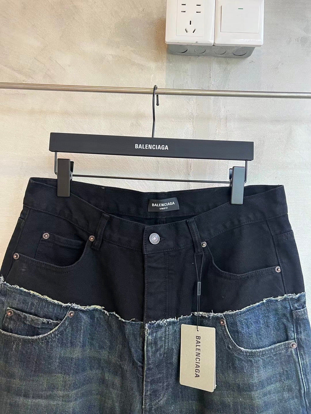 Two-tone denim jeans with button closure, front pockets, and contrast patchwork panels.