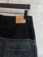 Dark denim jeans with waistband details and contrast patch panel along distressed hem.