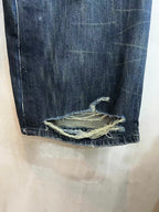 Denim jeans bottom hem with frayed edge and overlocked repairs at the cuff.