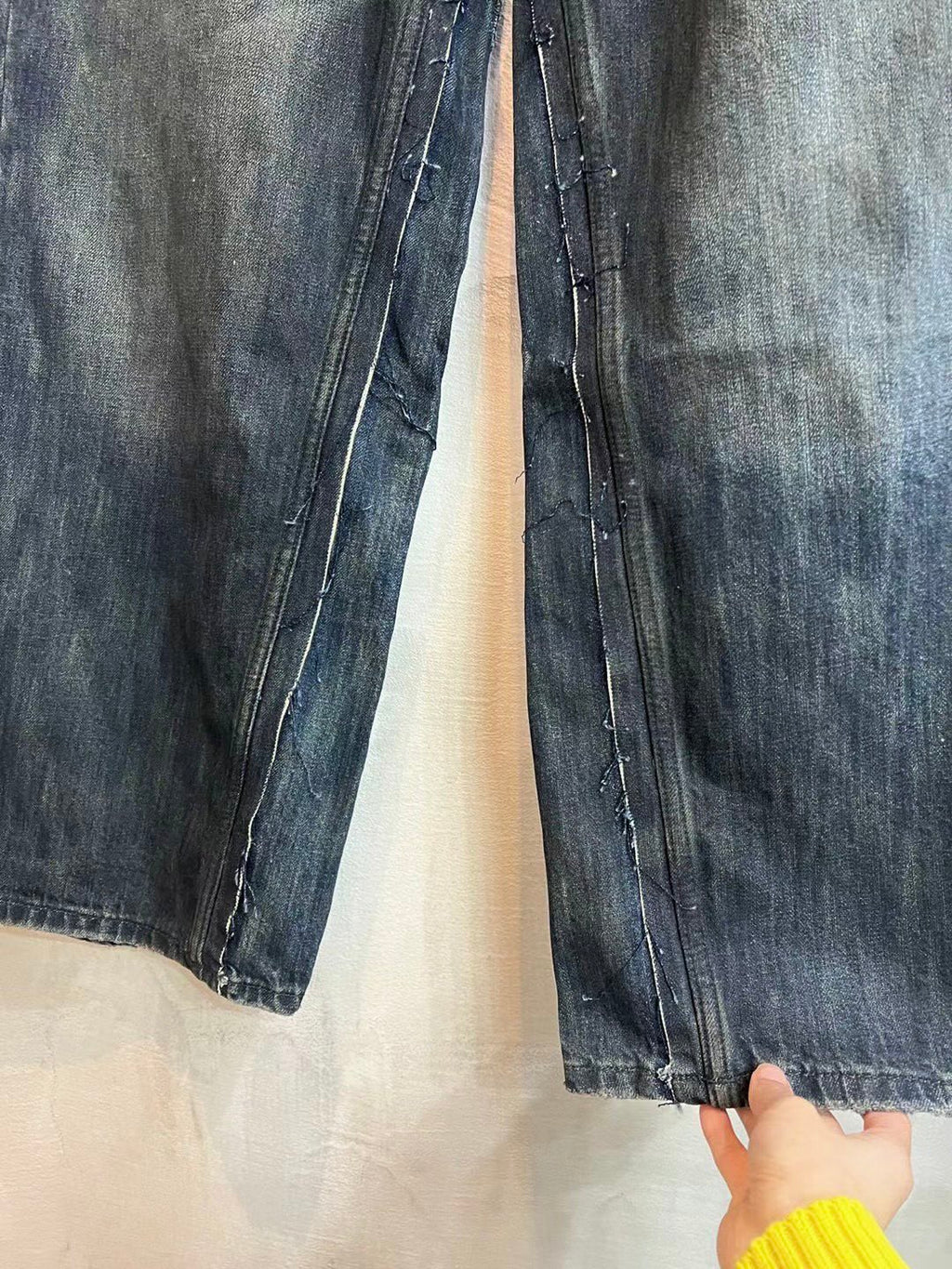 Denim jeans leg with visible stitching, zipper fly area, and worn wash texture.