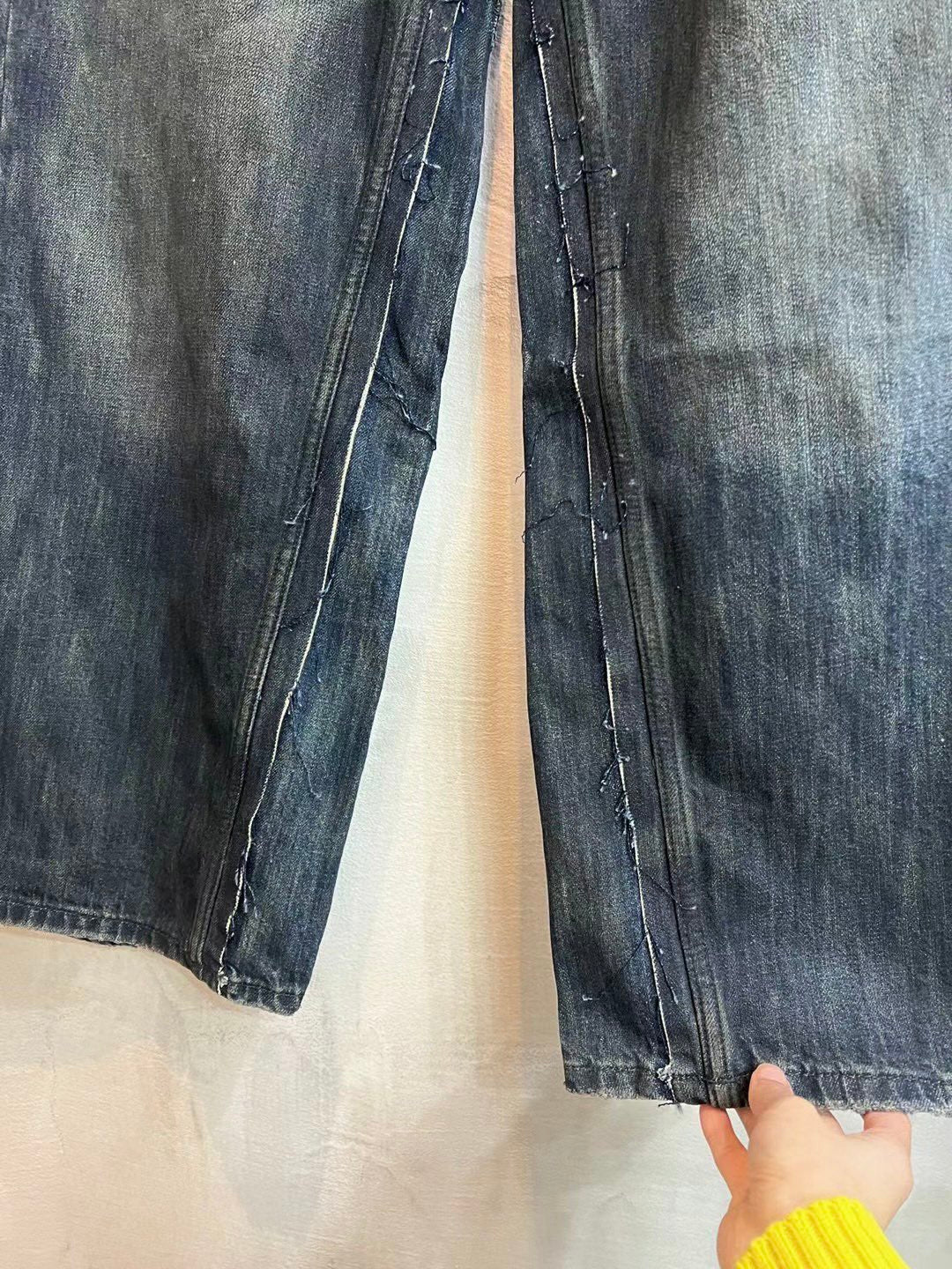 Denim jeans leg with visible stitching, zipper fly area, and worn wash texture.